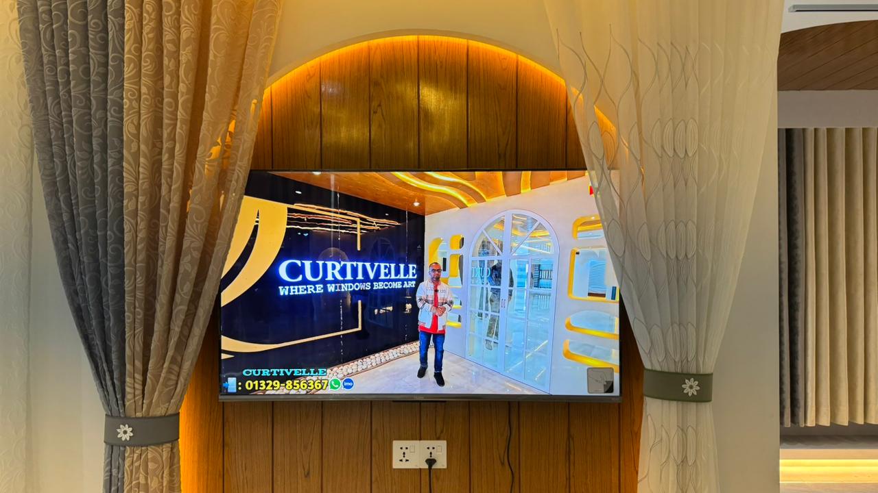 Curtivelle showroom TV display framed by premium curtains and warm lighting